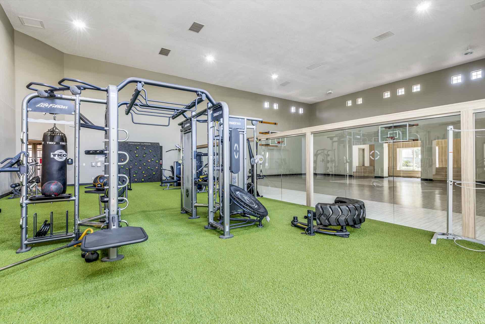 Weight room with artificial turf, climbing wall, punching bag, and indoor basketball court